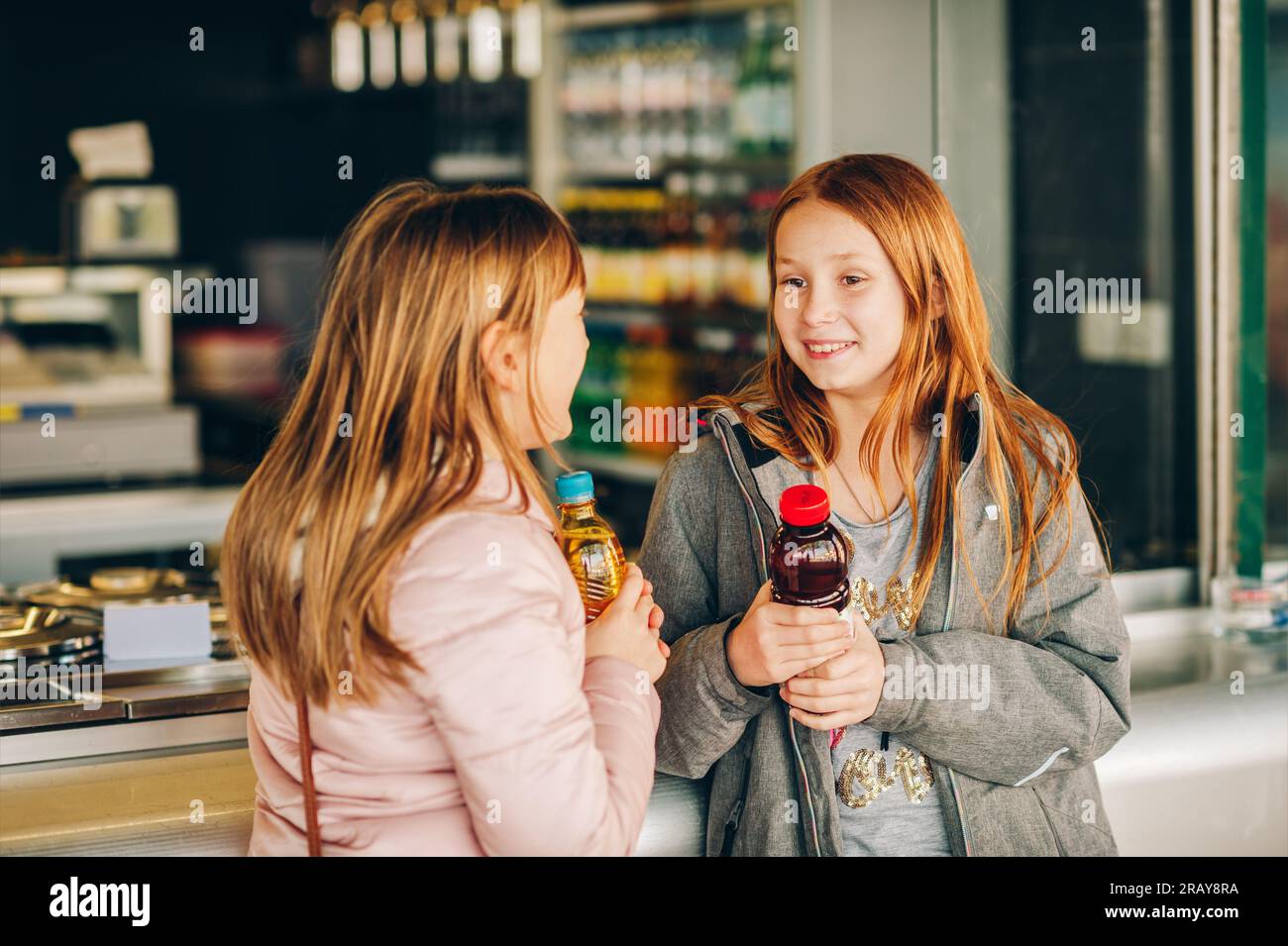 Deux petites filles achetant de la boisson dans des bouteilles en plastique Banque D'Images