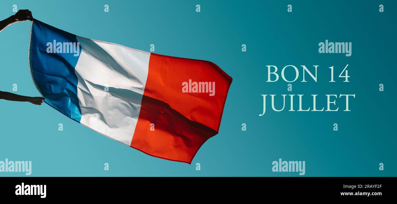 Tient un drapeau français agitant sur les airs et le texte bon 14 juillet, joyeux 14 juillet, fête nationale de la France écrit en français, dans un format panoramique Banque D'Images