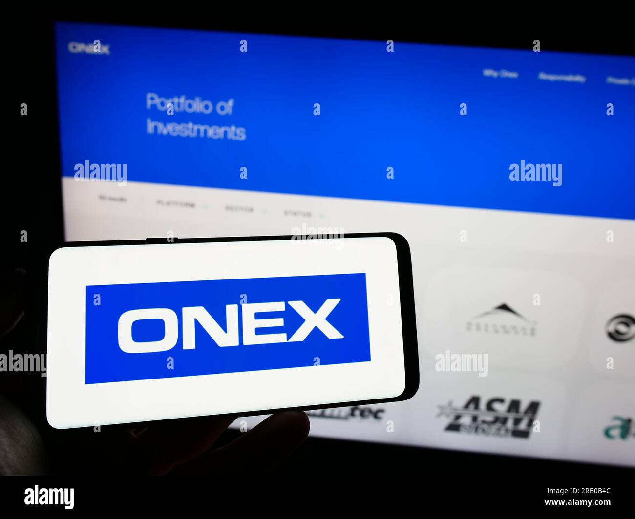 Personne détenant un téléphone cellulaire avec le logo de la société d'investissement canadienne Onex Corporation à l'écran devant la page Web. Concentrez-vous sur l'affichage du téléphone. Banque D'Images