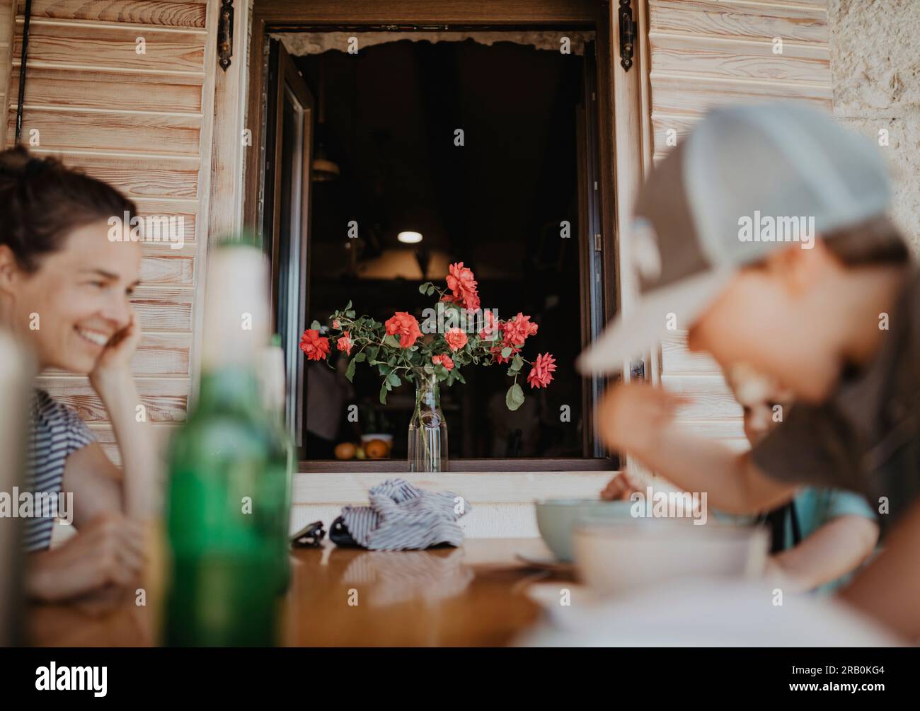 Mère assise avec les enfants à la table à manger sur la terrasse Banque D'Images