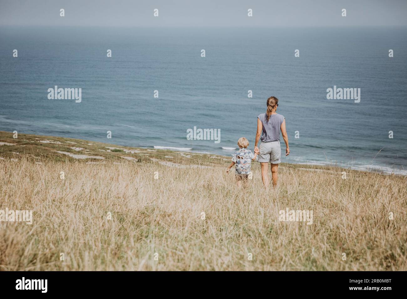 Mère et fils debout sur la prairie regardant la mer, Espagne Banque D'Images