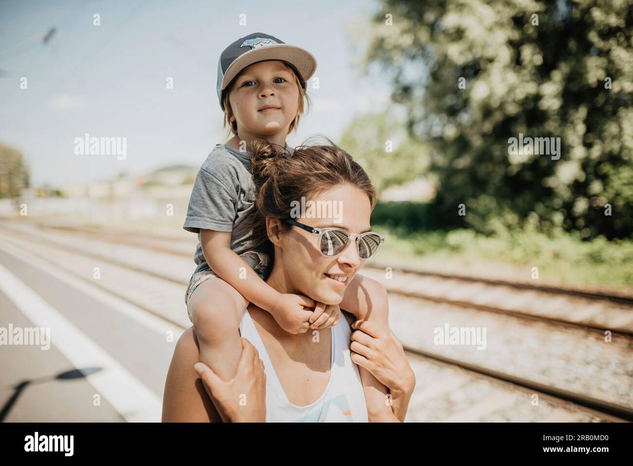 Mère porte son fils sur son épaule sur un quai de train Banque D'Images