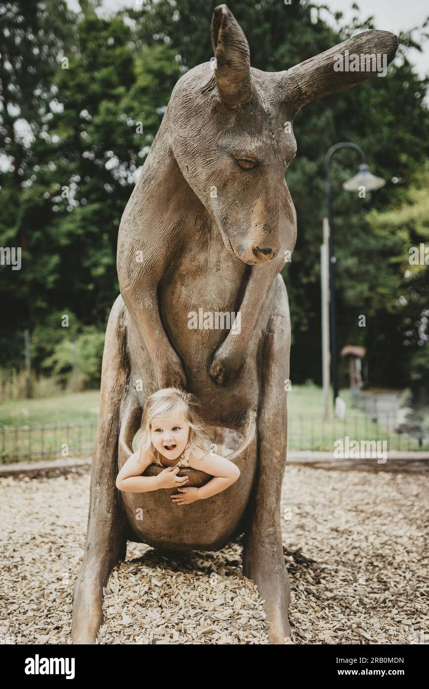Fille assise dans la poche d'un kangourou en bois, zoo de Dortmund Banque D'Images