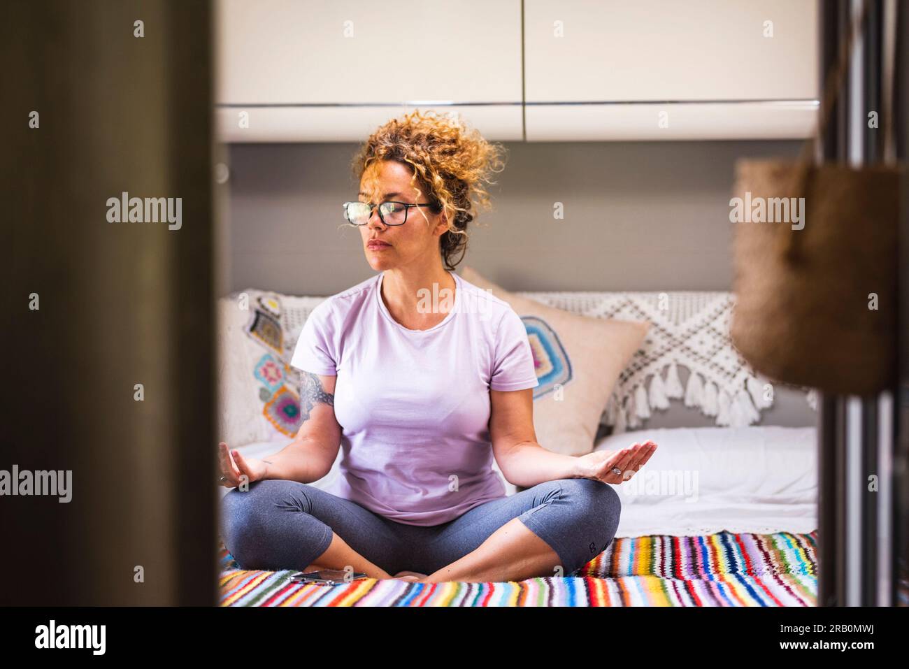 Méditation intérieure concept de style de vie sain activité de loisirs. Une femme en position lotus yoga assise sur le lit dans la chambre camping-car. Personnes sereines et exercice conscient. Les soins de santé spirituels. Équilibre Banque D'Images