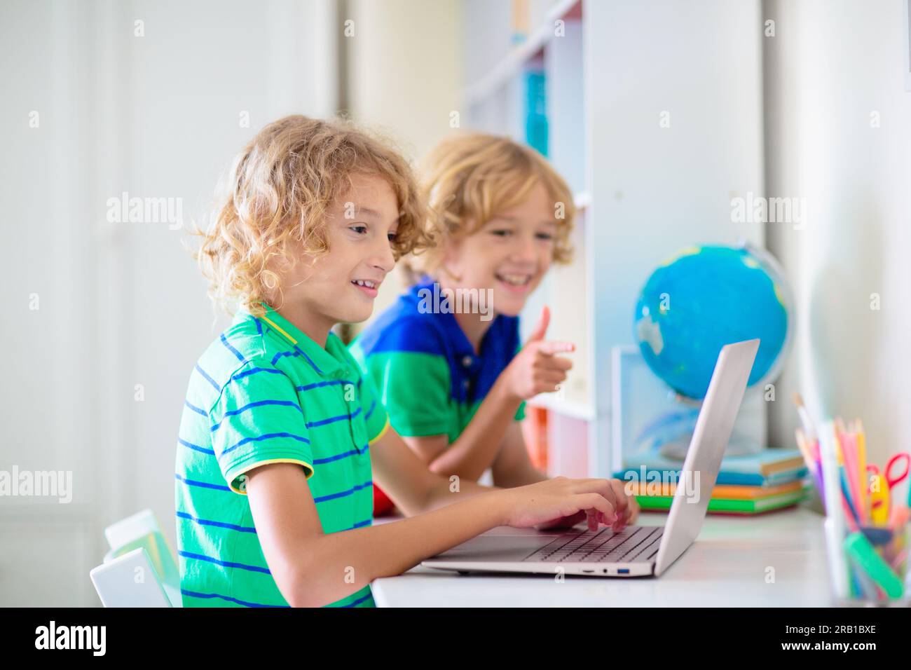 Enfant faisant ses devoirs sur ordinateur. Cours en ligne. Homeschooling et apprentissage à distance. Petit garçon d'école lisant sur l'écran de moniteur. Les enfants jouent à un jeu vidéo. Banque D'Images