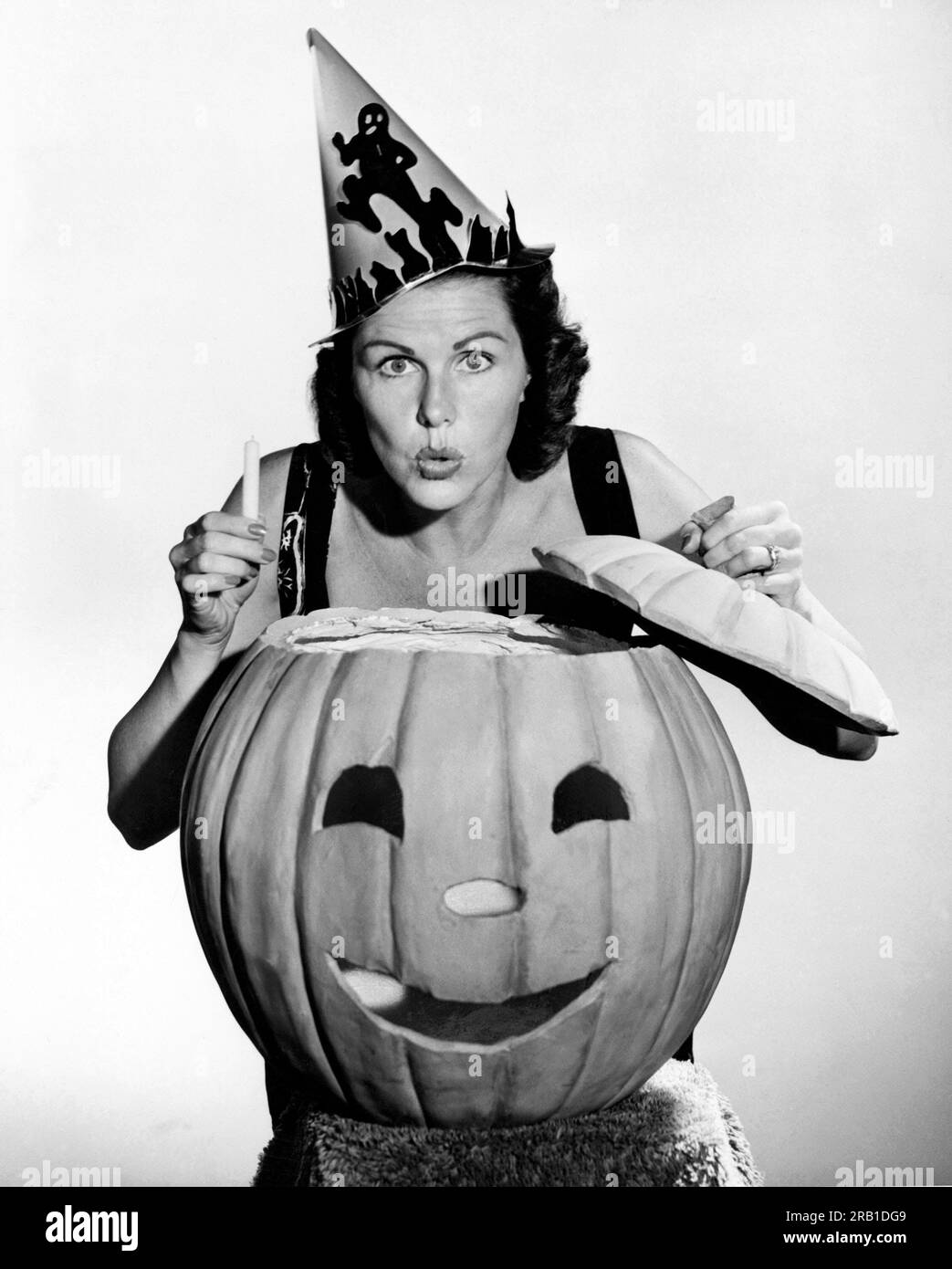 États-Unis : c. 1940 Une femme qui a l'air effrayante avec une citrouille et une bougie à Halloween. Banque D'Images