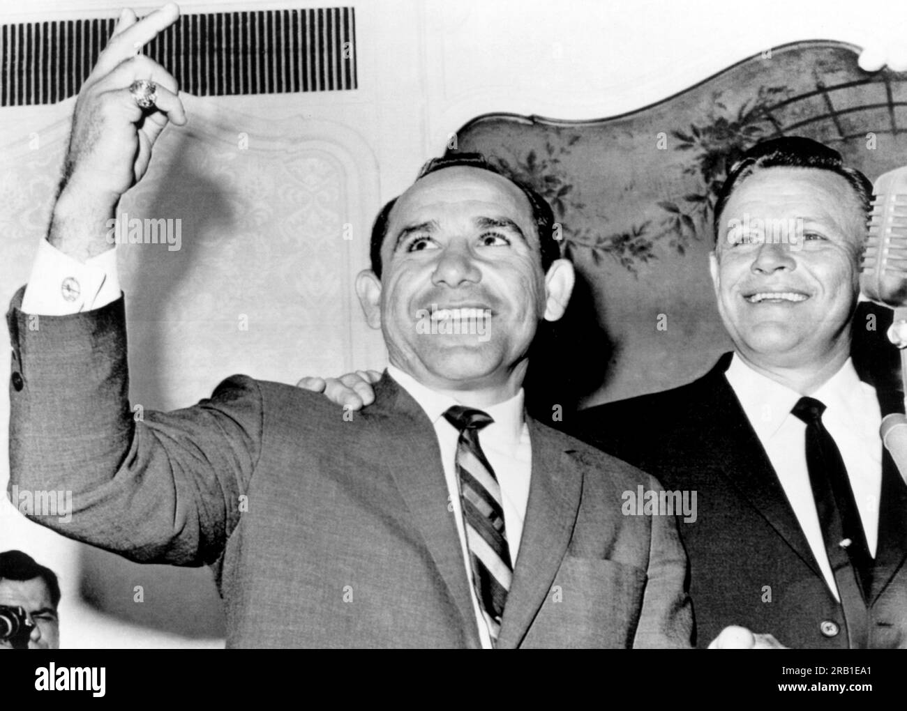 New York, New York : 24 octobre 1963 le Manager des New Yankees Yogi Berra clignote le signe de la victoire après avoir été nommé pour succéder à Ralph Houk (à droite) en tant que Manager des éternels champions de la Ligue américaine. Berra a immédiatement annoncé sa retraite en tant que joueur avec 358 home runs et un troupeau de records de la série mondiale. Banque D'Images