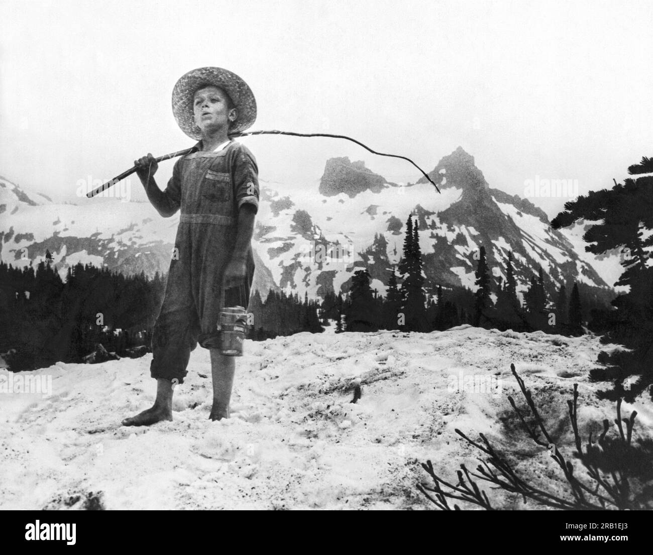 Mt. Rainier National Park, Washington : 16 juillet 1925 Un garçon pieds nus fait une randonnée dans la neige dans Paradise Valley pour aller pêcher. Banque D'Images