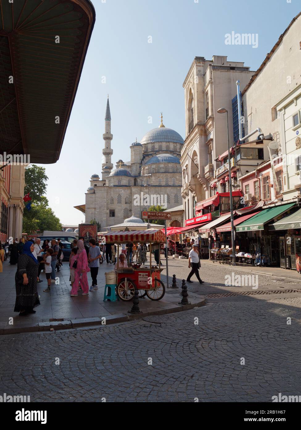 Yeni Cami ou Nouvelle Mosquée avec une rue pleine de magasins, de gens et un chariot distributeur rouge, Istanbul, Turquie Banque D'Images