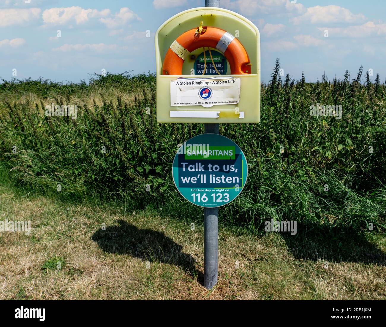 Un panneau pour les Samaritains près d'une bouée annulaire avec un panneau indiquant qu'une bouée annulaire volée est une vie volée, sur la côte à Co louth, en Irlande. Banque D'Images