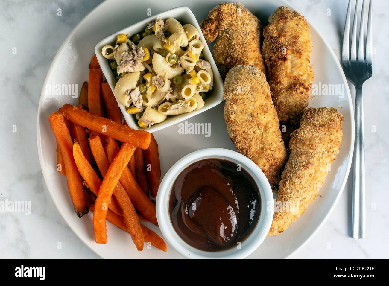 filets de poulet et frites de patates douces servis avec salade de macaroni au thon Banque D'Images