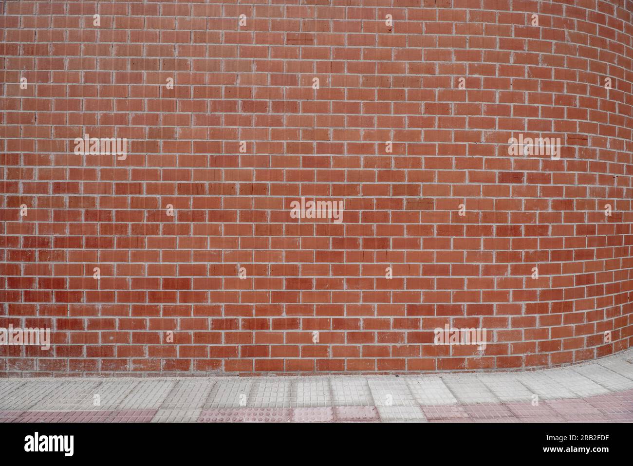 Un mur de briques râpées sur une rue vide de la ville Banque D'Images