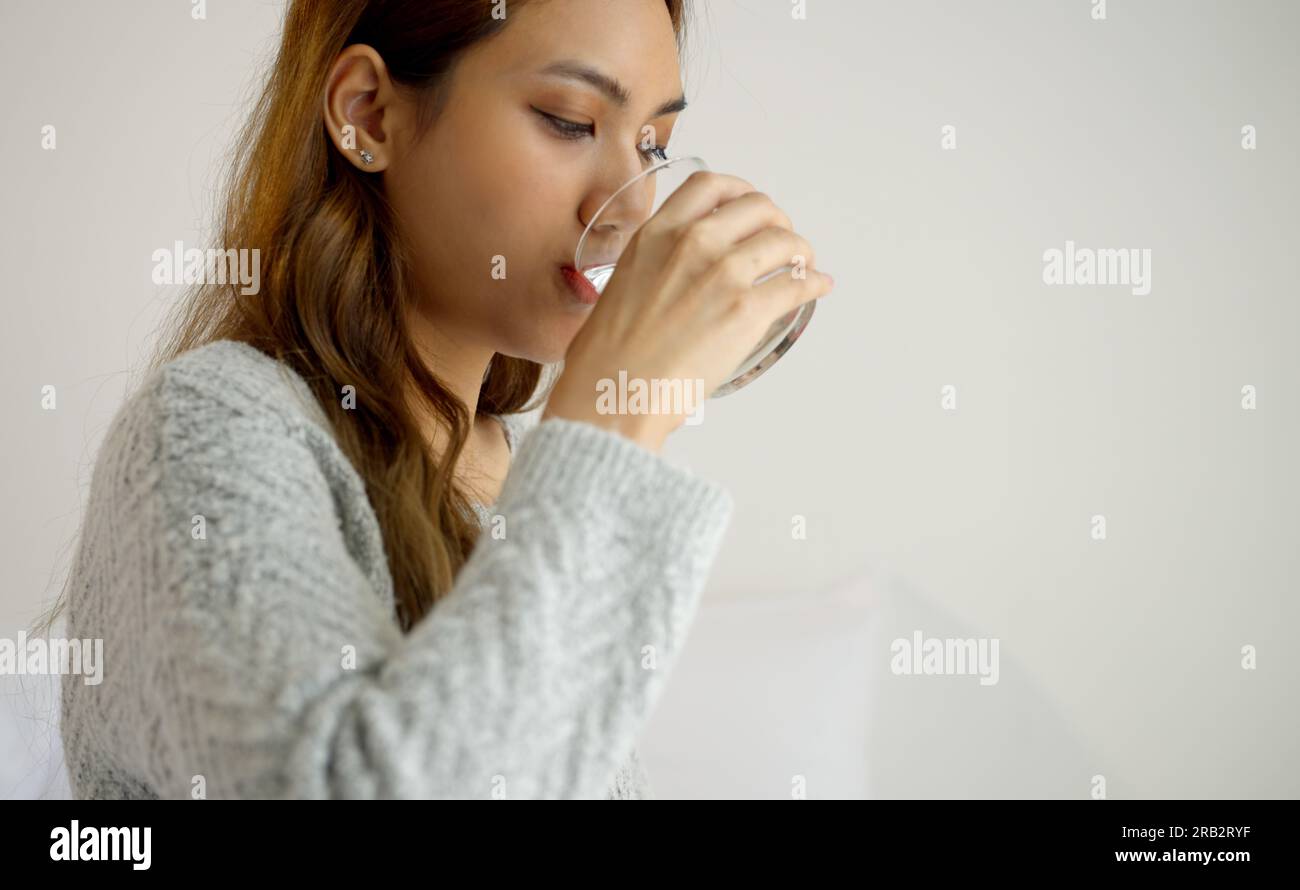 Jeune femme buvant un verre d'eau fraîche le matin. Banque D'Images