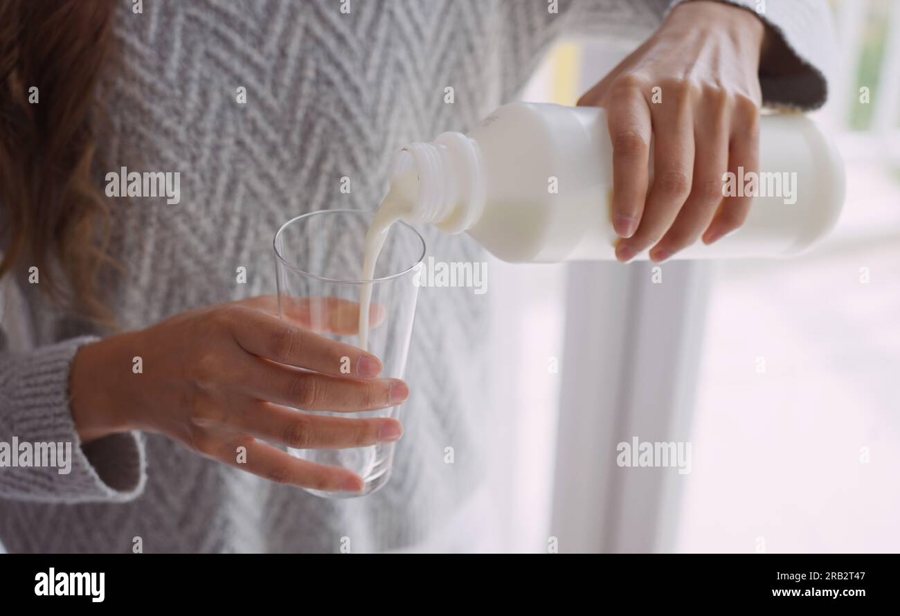 Jeune femme versant du lait dans le verre. Banque D'Images