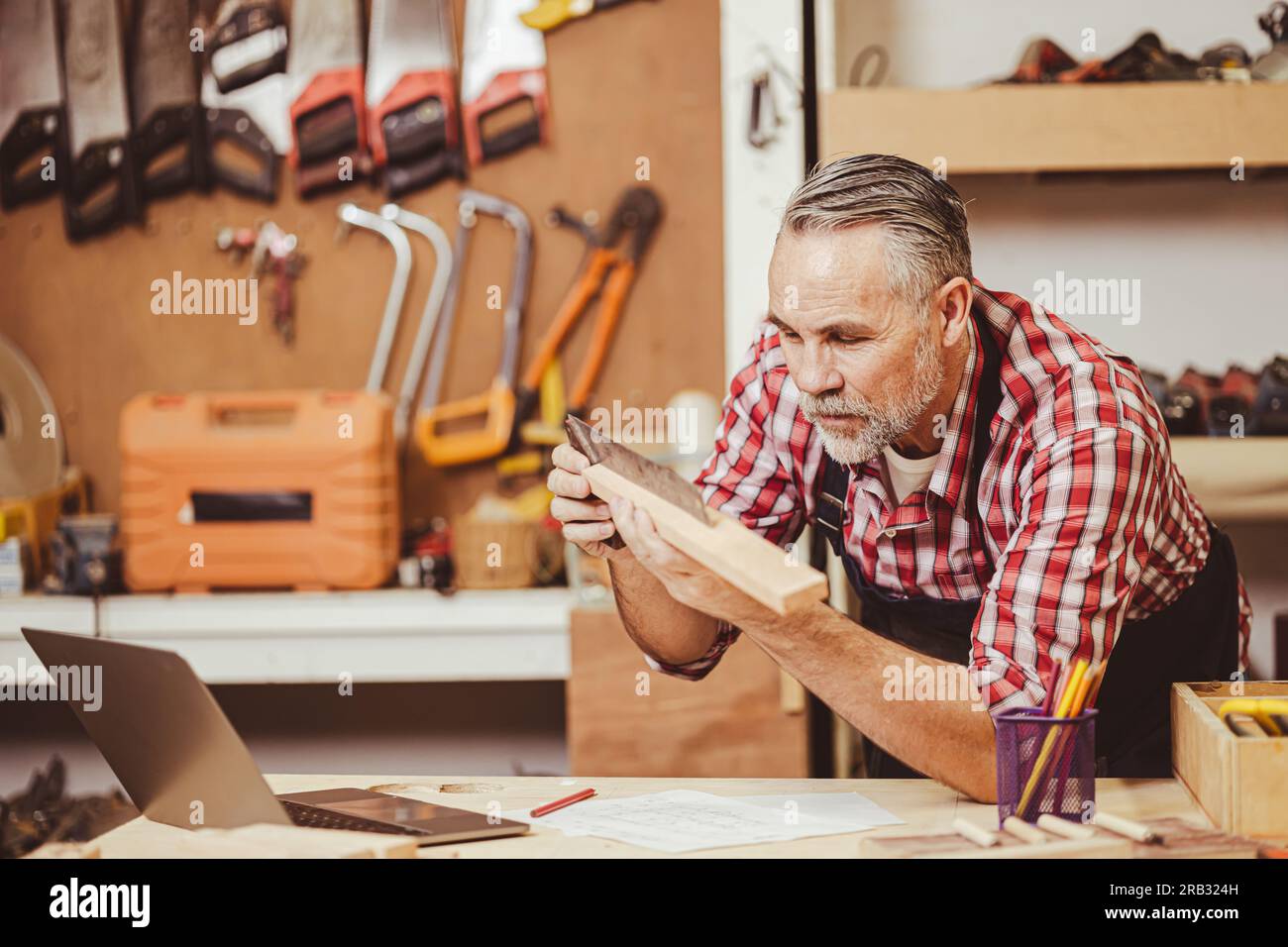 Professionnel senior masculin caucasien diy bois travaillant faisant des meubles à la maison dans l'atelier, rénovation de la maison. Banque D'Images