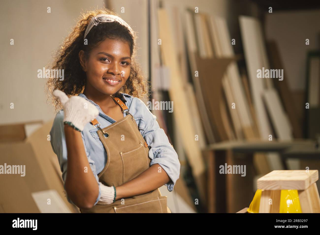 Heureuse menuisière femme africaine noire souriante dans l'atelier de bois Profitez de faire des affaires de meubles en bois faits à la main. Banque D'Images