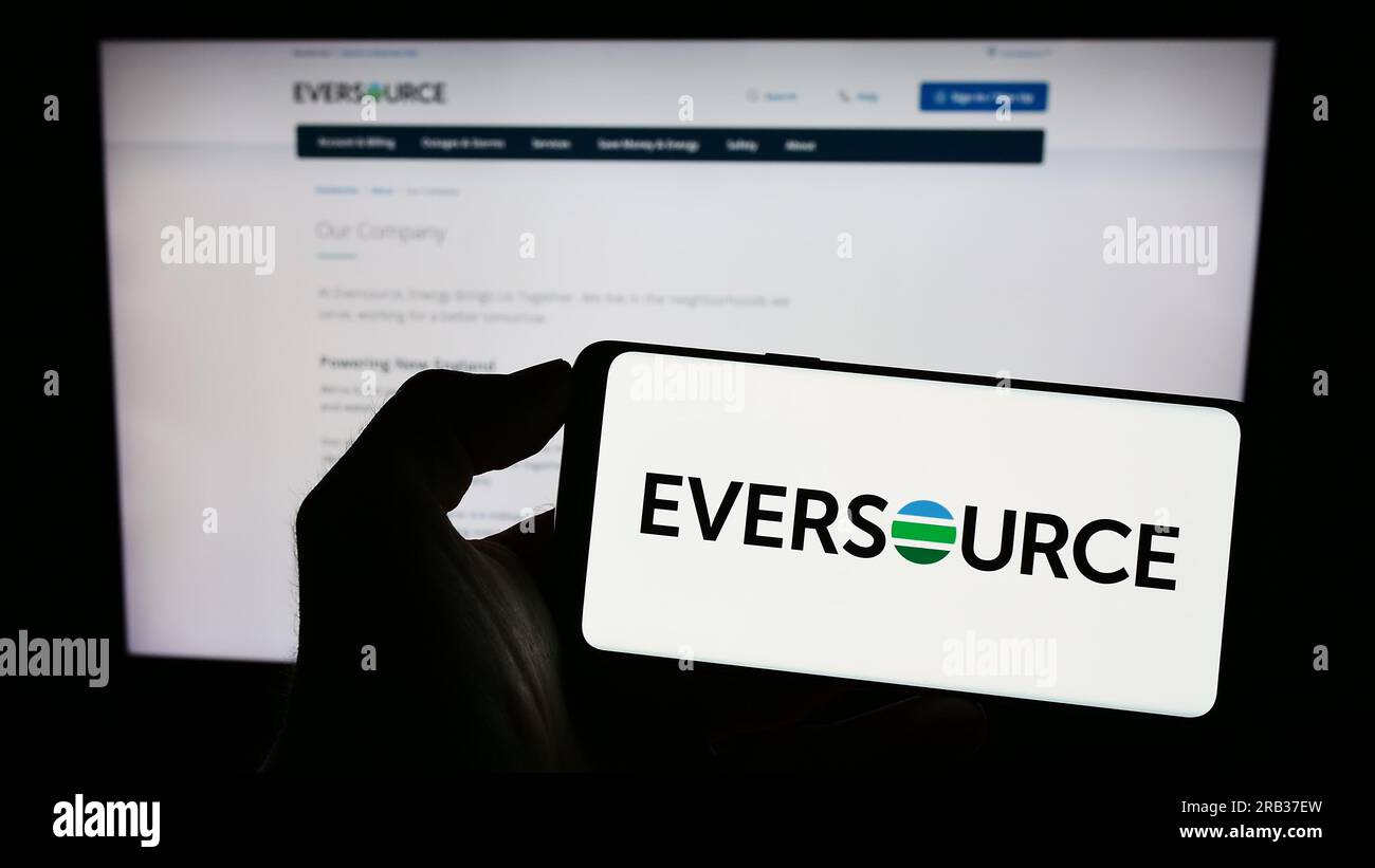 Personne tenant le téléphone mobile avec le logo de la société de services publics américaine Eversource Energy sur l'écran en face de la page Web. Concentrez-vous sur l'affichage du téléphone. Banque D'Images