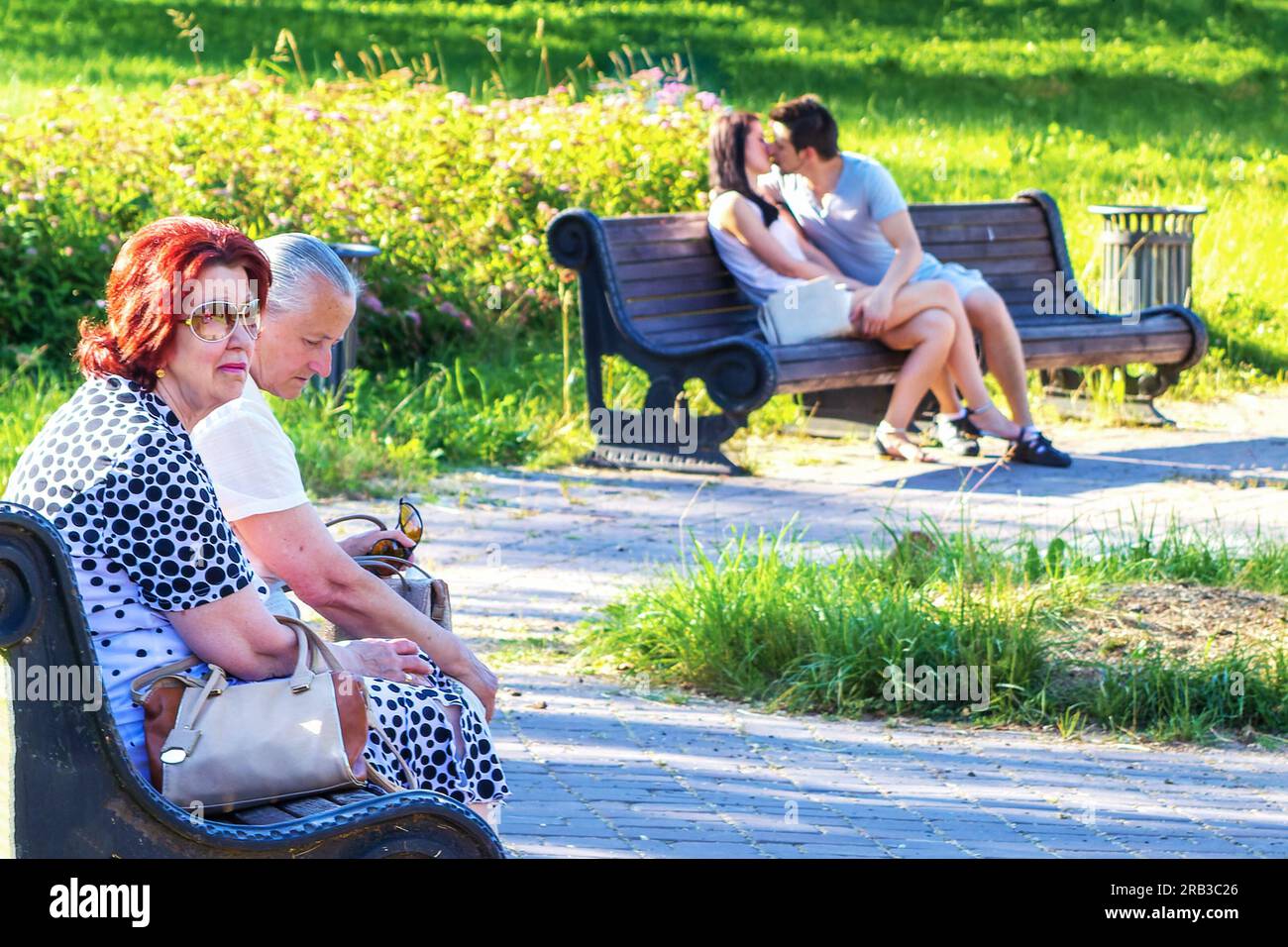 Minsk, Biélorussie - 03 juillet 2015 : une scène contrastée dans le parc. Deux couples sur un banc - vieux et jeune Banque D'Images