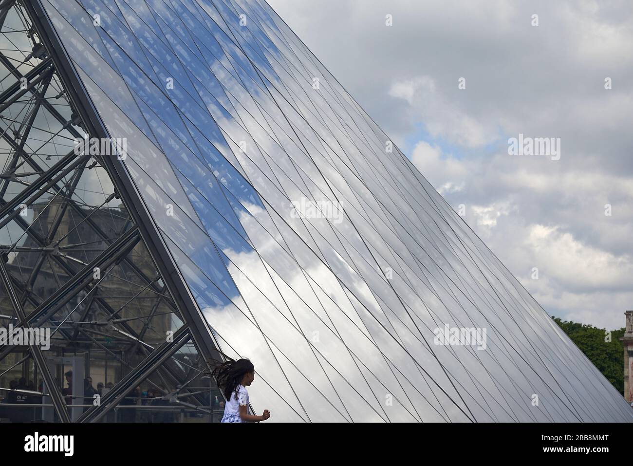Fille asiatique courant au bâtiment de pyramide de verre au musée du Louvre Banque D'Images