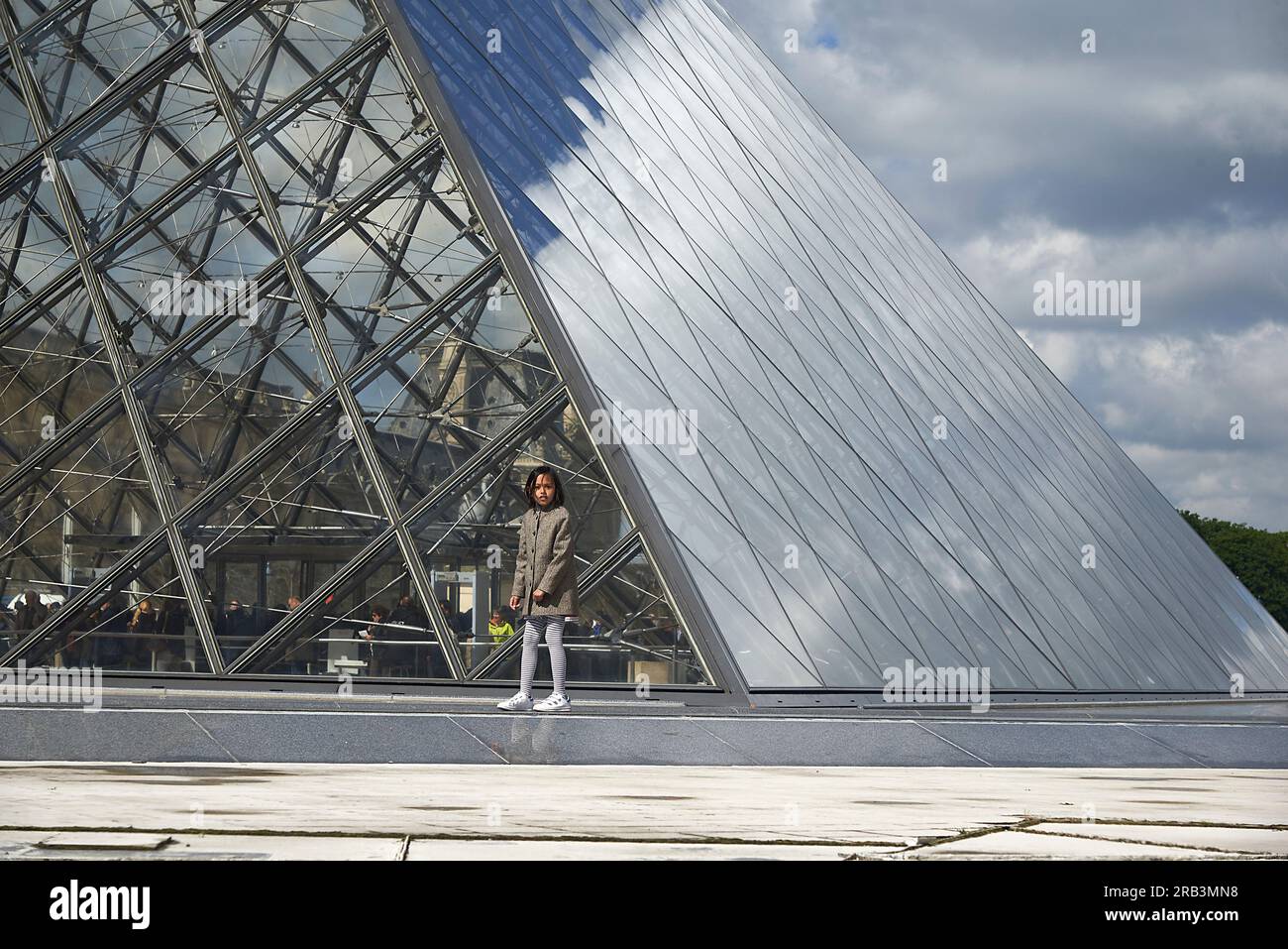 Fille asiatique posant dans le bâtiment de pyramide de verre devant au musée du Louvre Banque D'Images