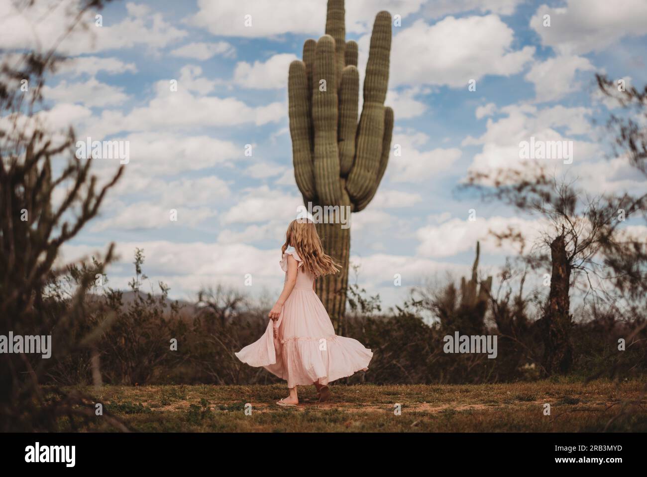 Fille tournoyant dans le désert avec des cactus Banque D'Images