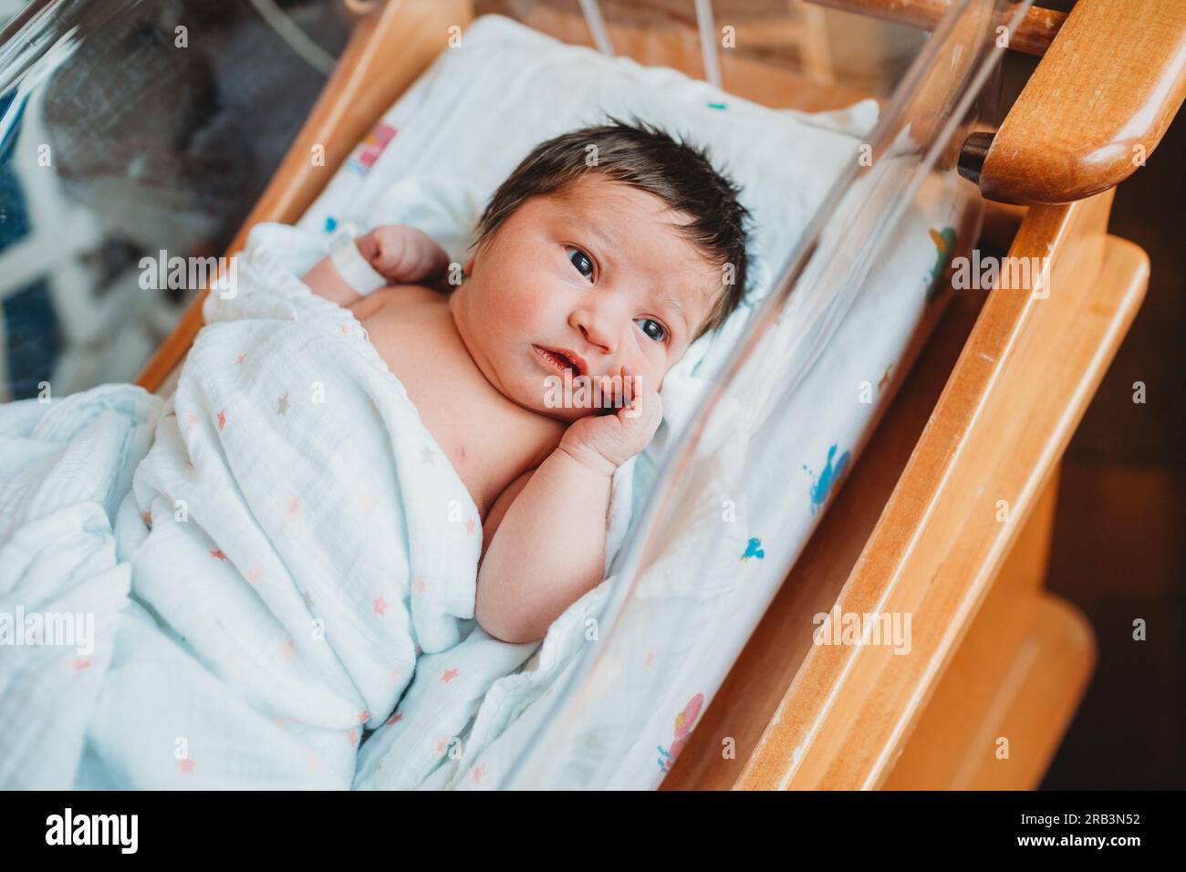 Nouveau-né éveillé dans son lit d'hôpital Banque D'Images