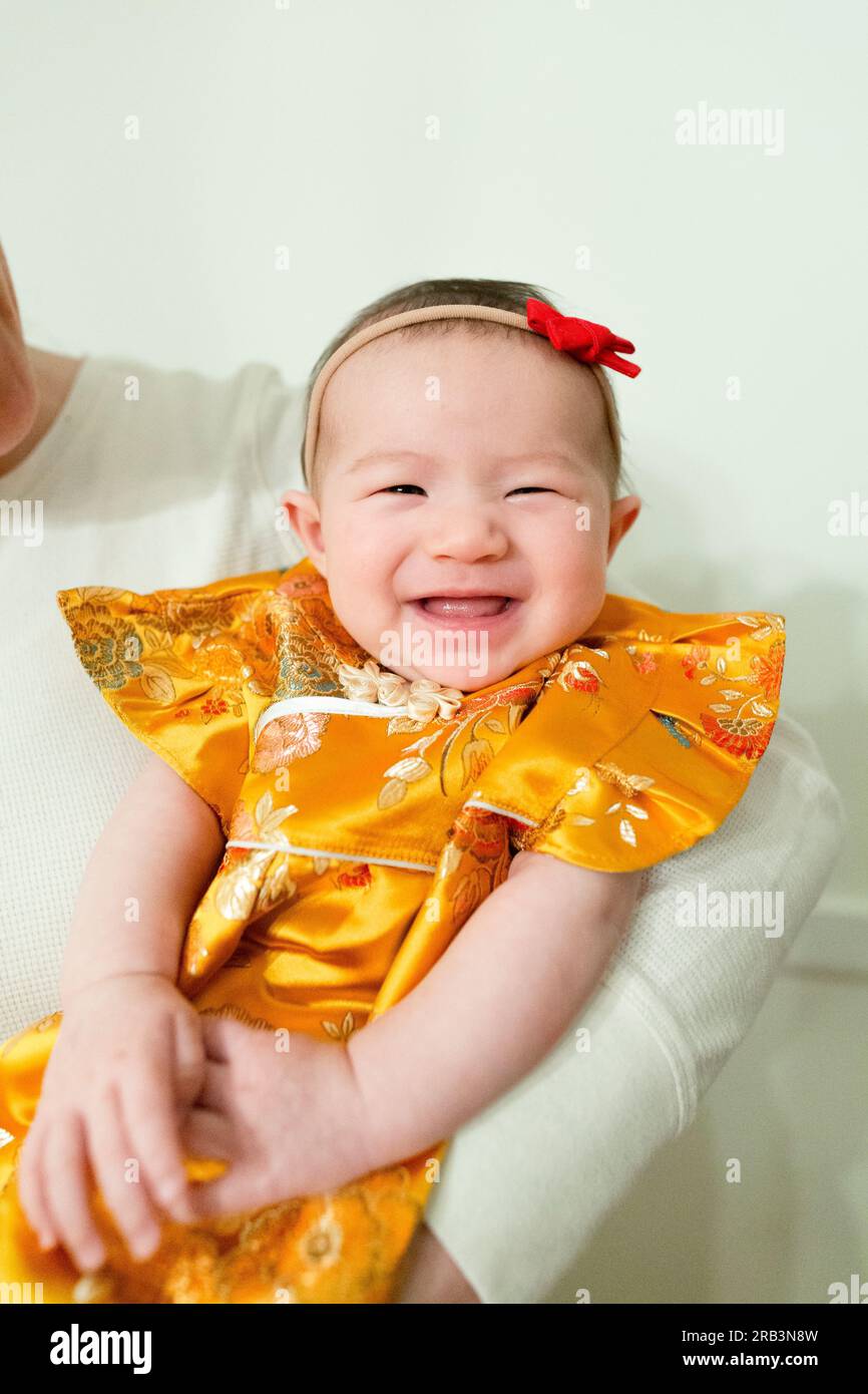 Bébé fille heureuse et souriante portant une robe jaune traditionnelle pour la fête Banque D'Images