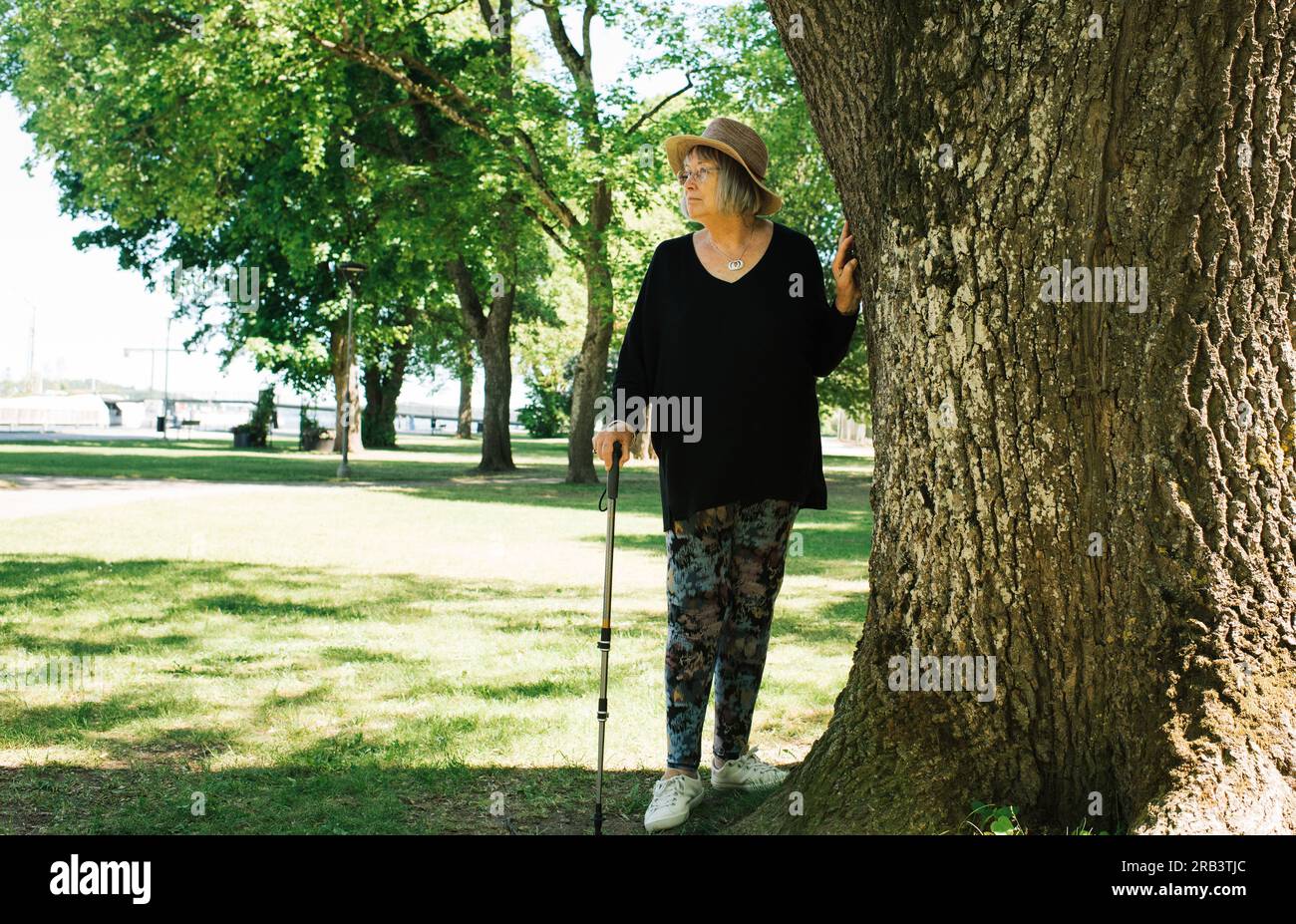 retraité faisant une pause de marcher avec un bâton dehors Banque D'Images