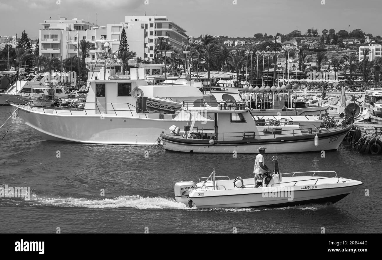 Ayia Napa, Chypre - 12 juin 2018 : bateau à moteur navigue sur la mer au port d'Agia Napa, les touristes marchent sur la côte par une journée ensoleillée. Photo noir et blanc Banque D'Images Ayia Napa, Chypre - 12 juin 2018 : bateau à moteur navigue sur la mer au port d'Agia Napa, les touristes marchent sur la côte par une journée ensoleillée. Photo noir et blanc Banque D'Images