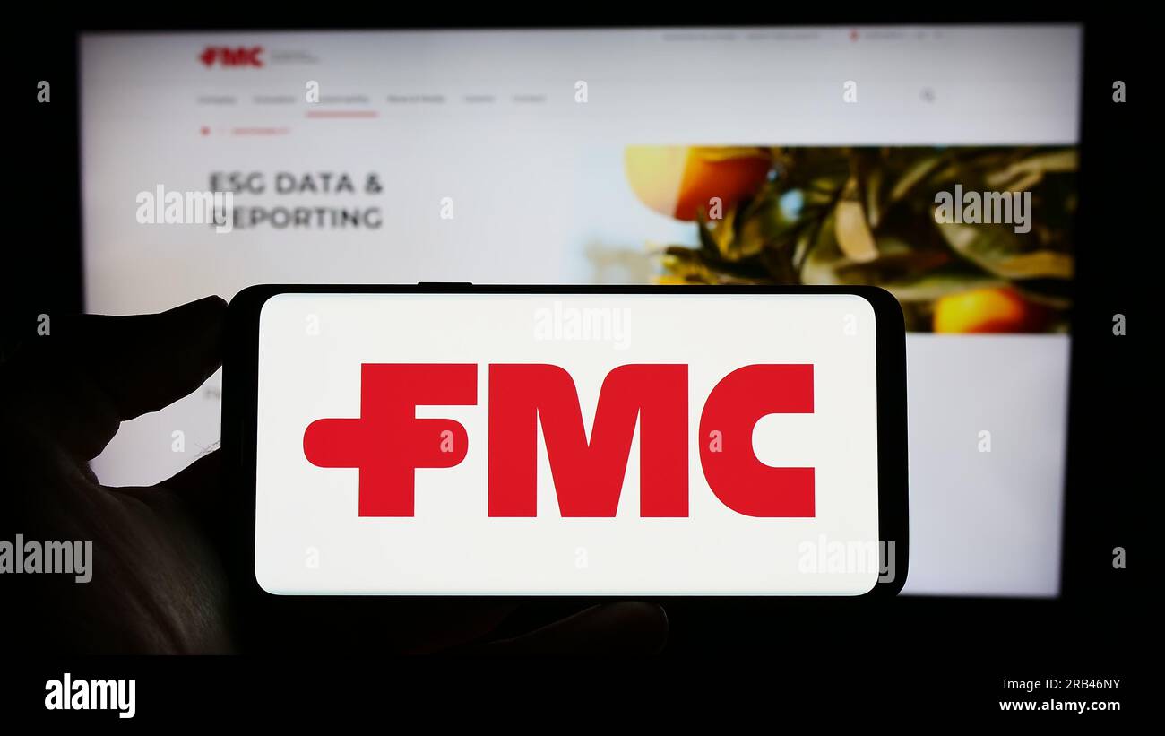 Personne tenant le téléphone portable avec le logo de la société chimique américaine FMC Corporation sur l'écran devant la page Web de l'entreprise. Concentrez-vous sur l'affichage du téléphone. Banque D'Images