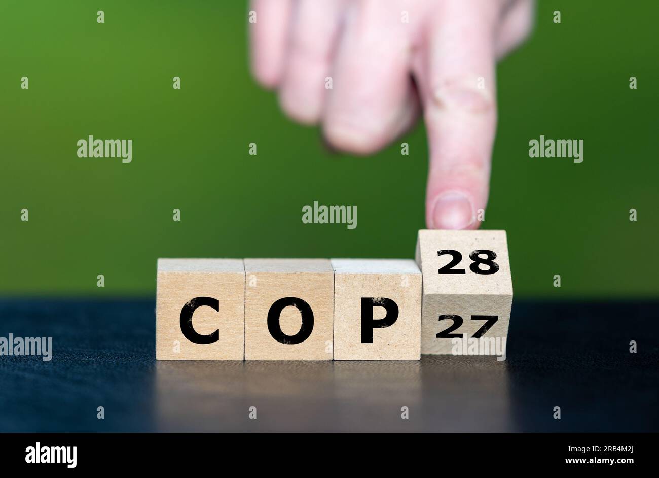Symbole pour la prochaine conférence sur le climat. La main tourne les cubes et change l'expression 'COP27' en 'COP28'. Banque D'Images