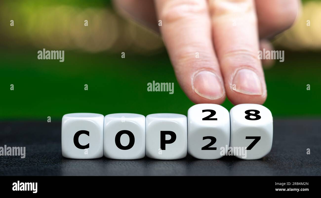 Symbole pour la prochaine conférence sur le climat. La main tourne les cubes et change l'expression 'COP27' en 'COP28'. Banque D'Images