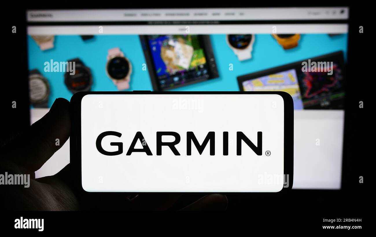 Personne tenant un smartphone avec le logo de la société technologique Garmin Ltd. Sur l'écran devant le site Web. Concentrez-vous sur l'affichage du téléphone. Banque D'Images