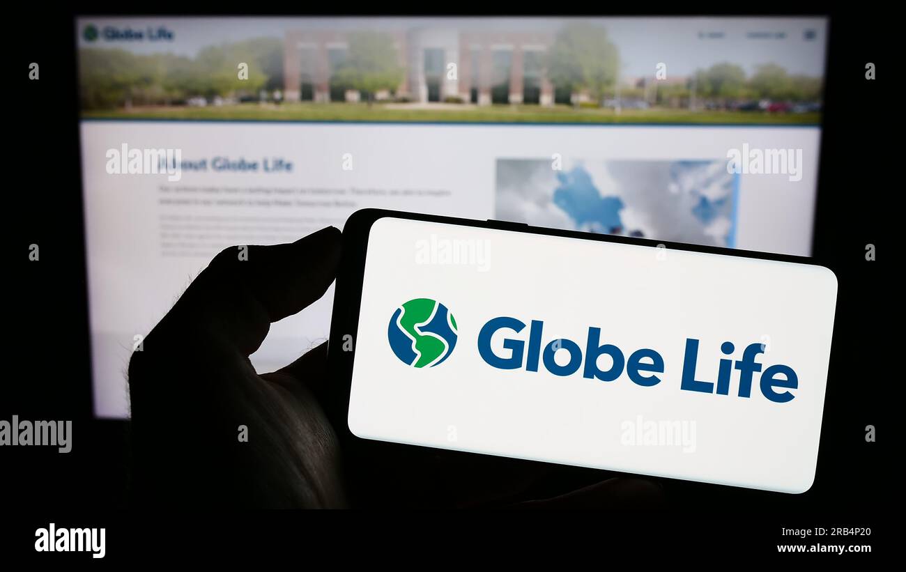 Personne détenant un téléphone cellulaire avec le logo de la compagnie d'assurance américaine Globe Life Inc. À l'écran devant la page Web de l'entreprise. Concentrez-vous sur l'affichage du téléphone. Banque D'Images