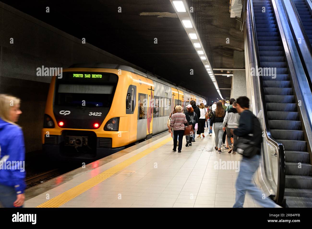 Train en gare avec des passagers sur le quai de la gare avec d'autres arrivant sur escalator, Portugal Banque D'Images