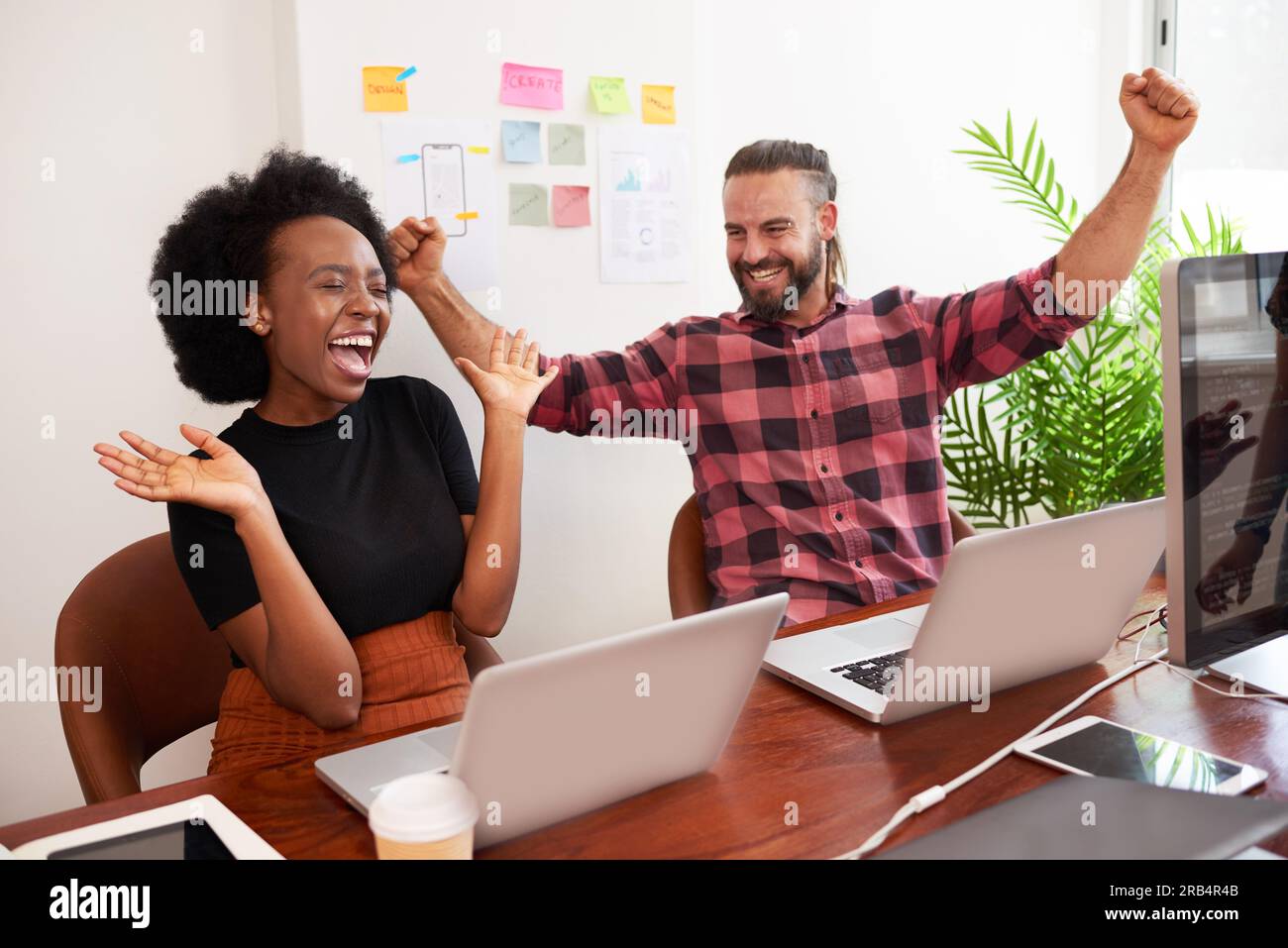 Deux développeurs acclament avec les bras levés dans le bureau, lancement réussi du produit Banque D'Images