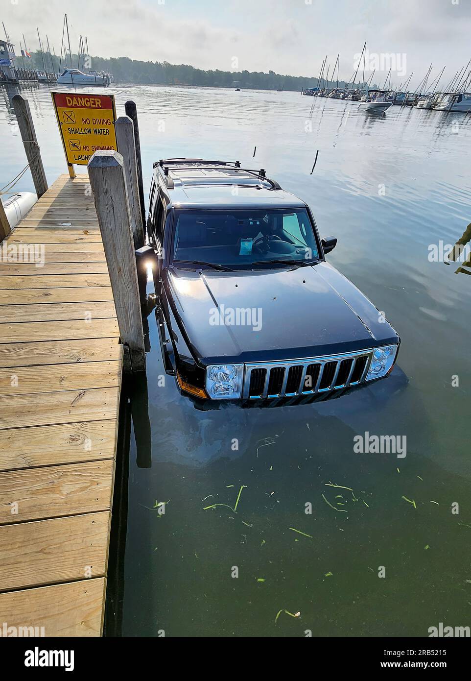 Véhicule SUV noir à moitié immergé dans l'eau d'un lac à côté d'un quai en bois Banque D'Images