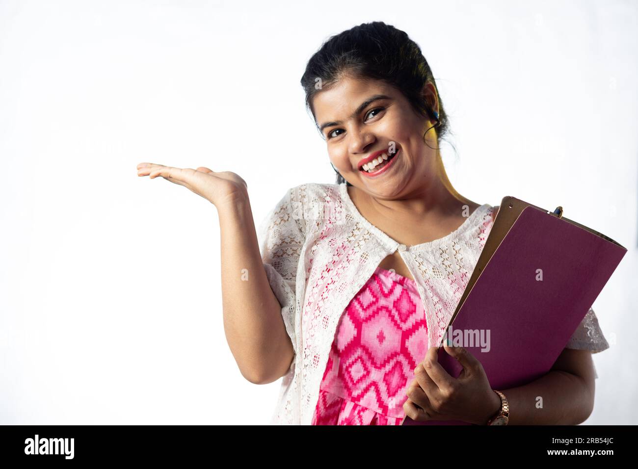 Une jolie jeune fille indienne avec des livres à la main debout avec le visage souriant sur fond blanc Banque D'Images