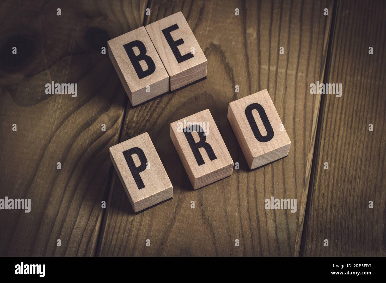 Cubes en bois formant les mots 'be pro' sur une table rustique en bois. Concept de croissance personnelle et de réussite professionnelle. Banque D'Images