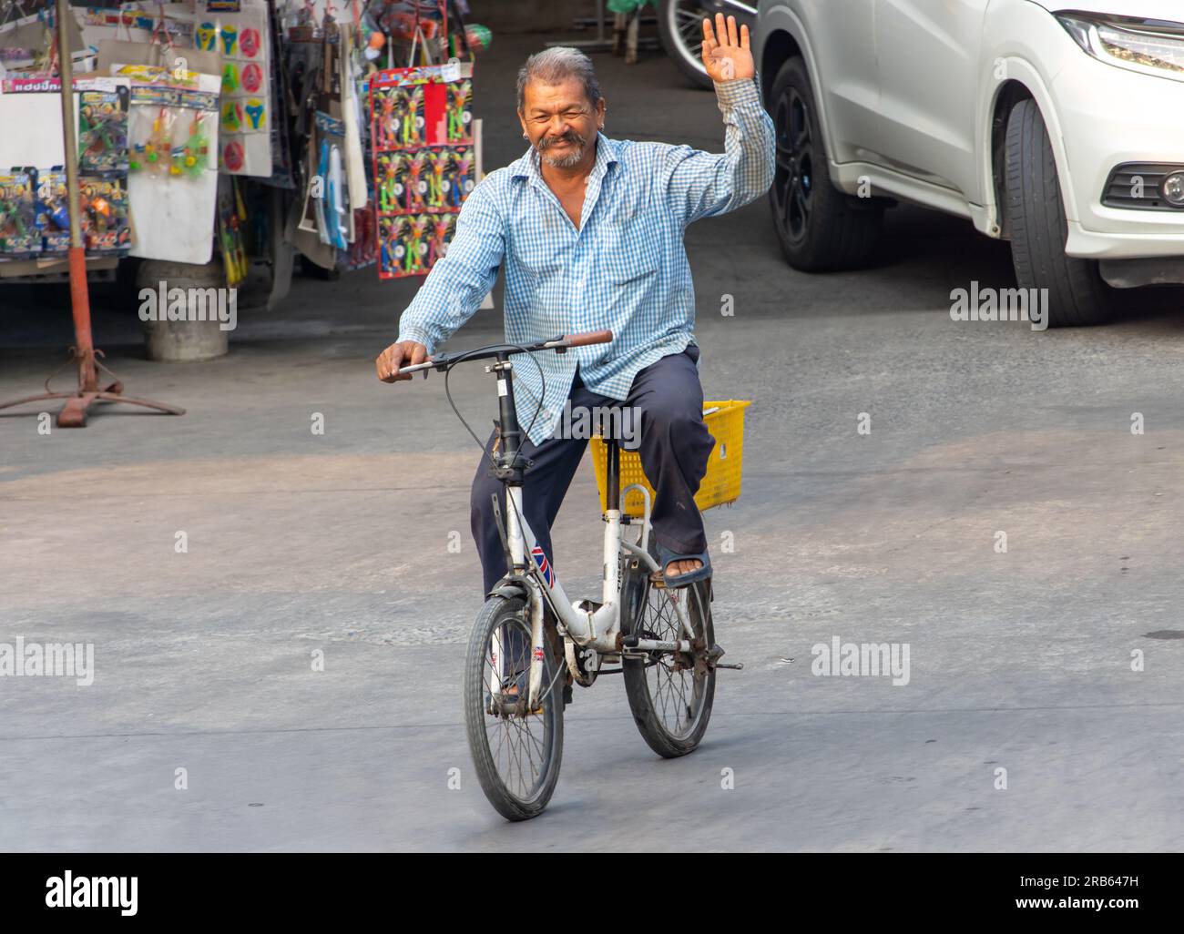 SAMUT PRAKAN, THAÏLANDE, 03 2023 MARS, un homme âgé monte à vélo dans la rue et salue la main levée Banque D'Images