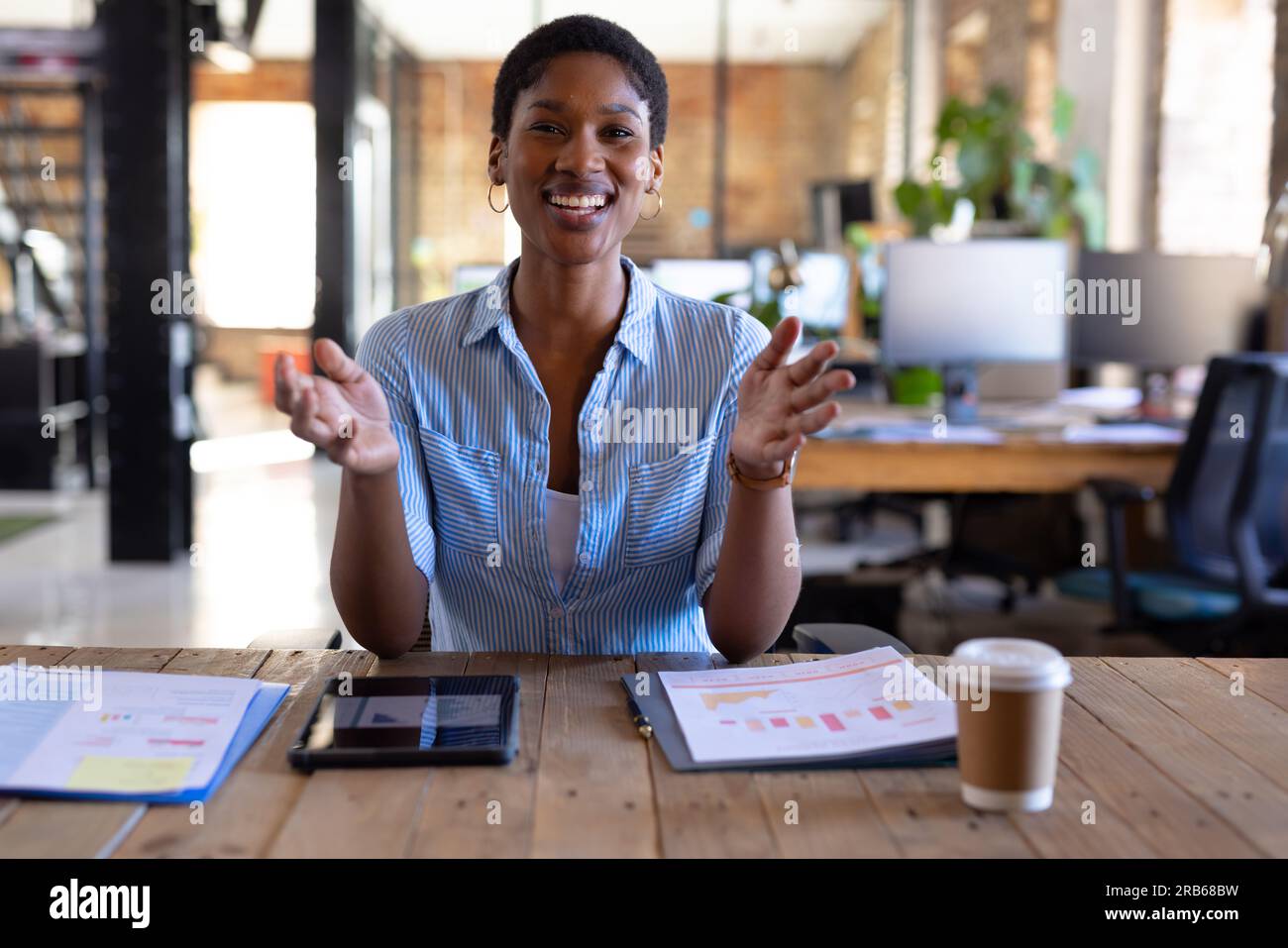 Portrait d'heureuse femme d'affaires afro-américaine occasionnelle ayant un appel vidéo et des gestes dans le bureau. Affaires, technologie et travail, inchangés. Banque D'Images