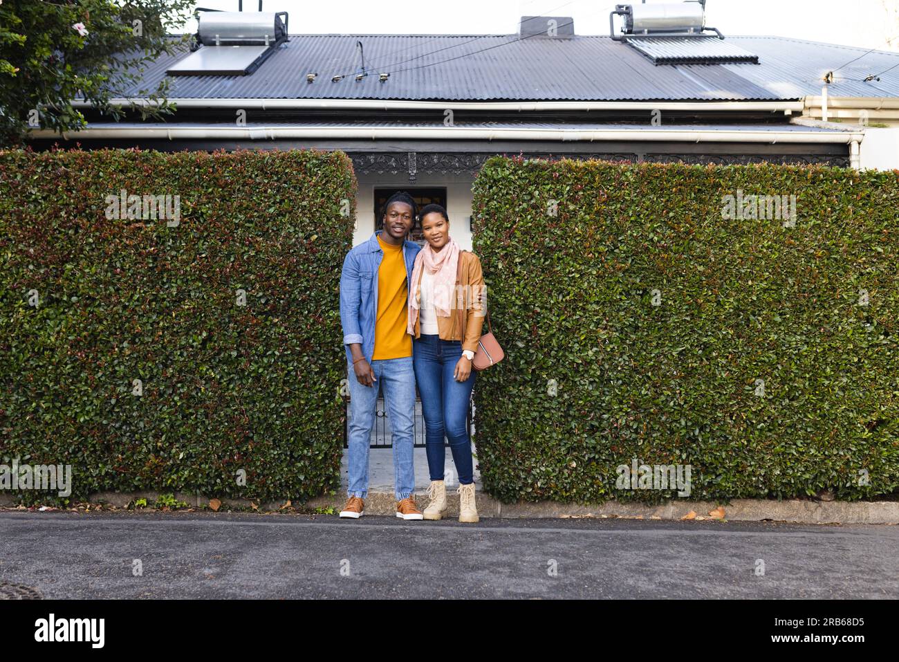 Portrait de jeune couple afro-américain debout près du mur de lierre vert à l'extérieur de la maison. Inaltéré, amour, unité, heureux, veste et concept de style de vie Banque D'Images Portrait de jeune couple afro-américain debout près du mur de lierre vert à l'extérieur de la maison. Inaltéré, amour, unité, heureux, veste et concept de style de vie Banque D'Images