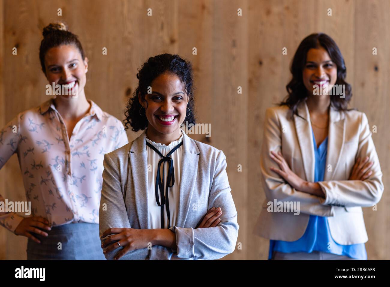 Portrait de femmes d'affaires occasionnelles heureuses diverses contre le mur en bois dans le bureau. Bureau décontracté, affaires, professionnel et de travail, inchangé. Banque D'Images