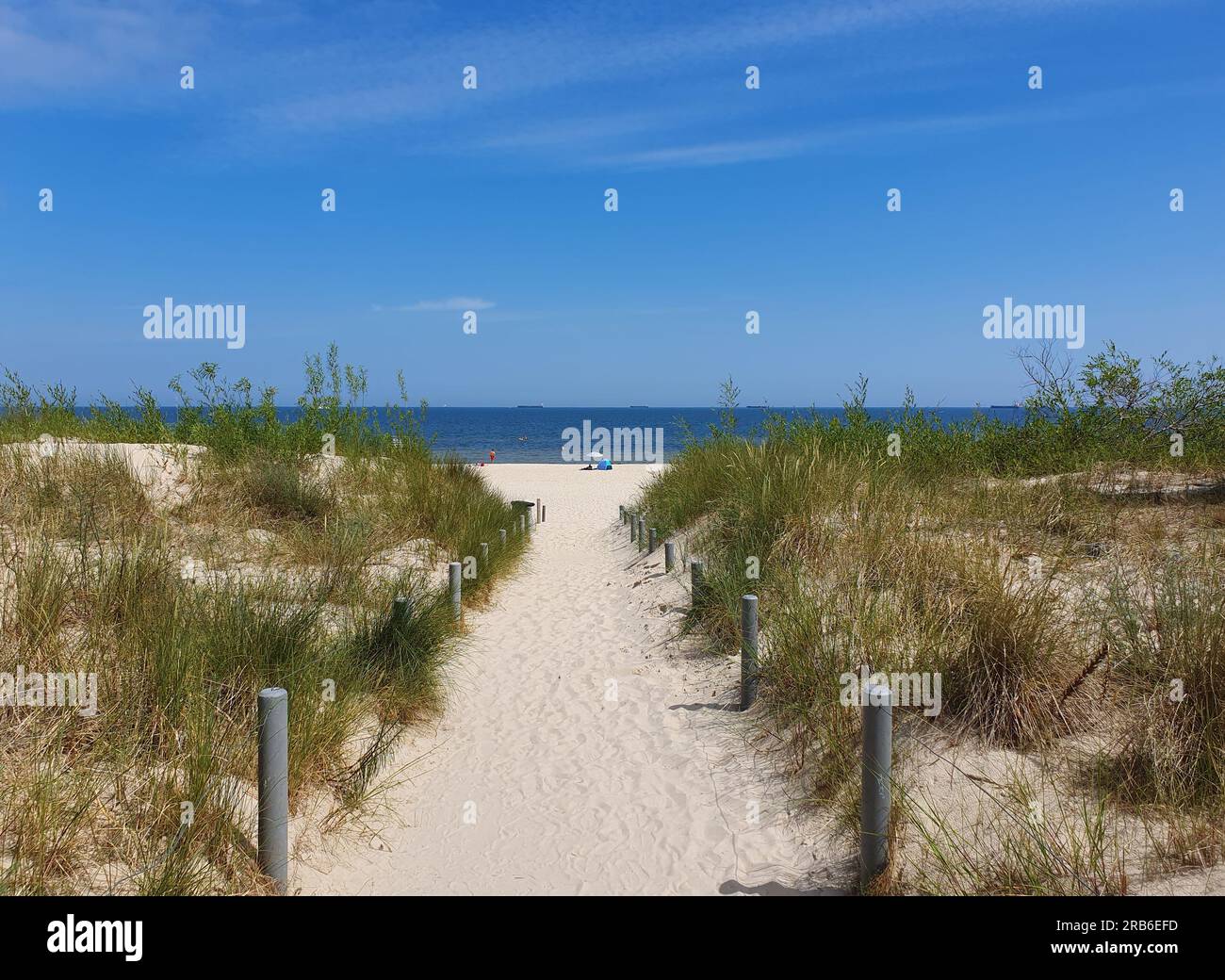 Un chemin de sable à la plage avec un ciel bleu. Banque D'Images