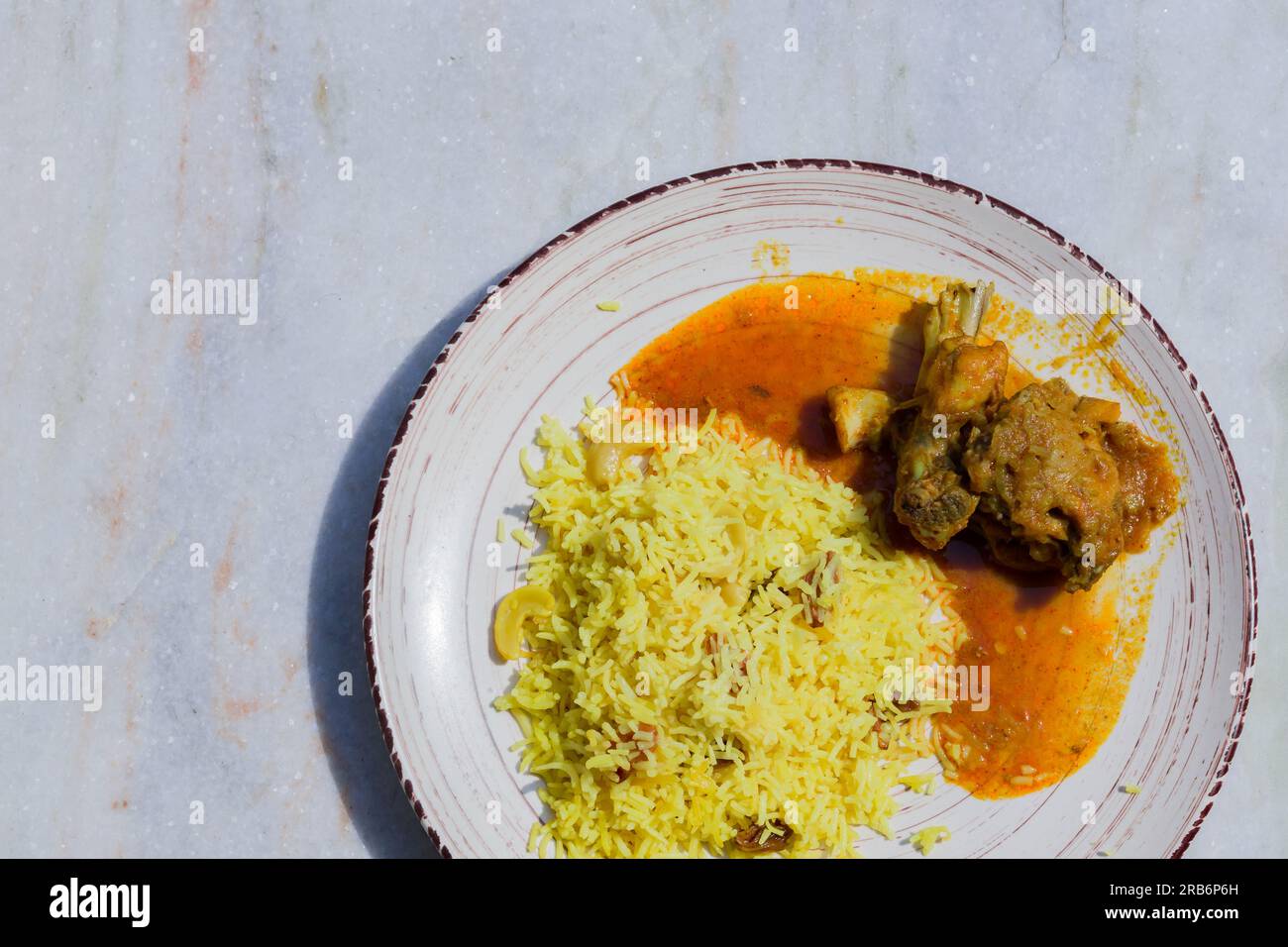 Pulav et curry de poulet servis sur une assiette. Traditionnel bengali basanti polao ou misti polao ou riz frit servi avec sauce au poulet. Banque D'Images