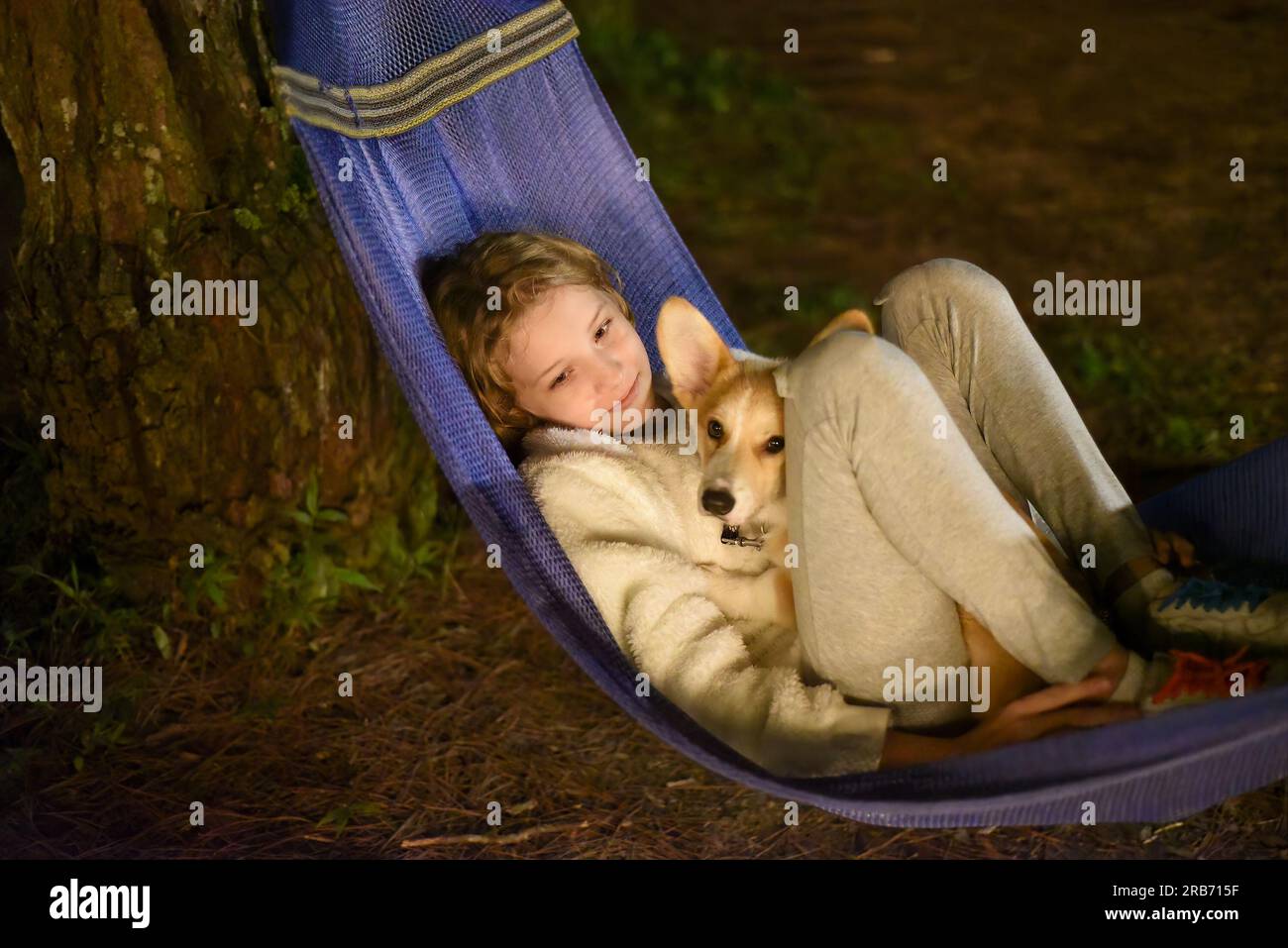 Petite fille mignonne dormant dans un hamac et tenant un chien de corgi ensemble dans un voyage de camping Banque D'Images