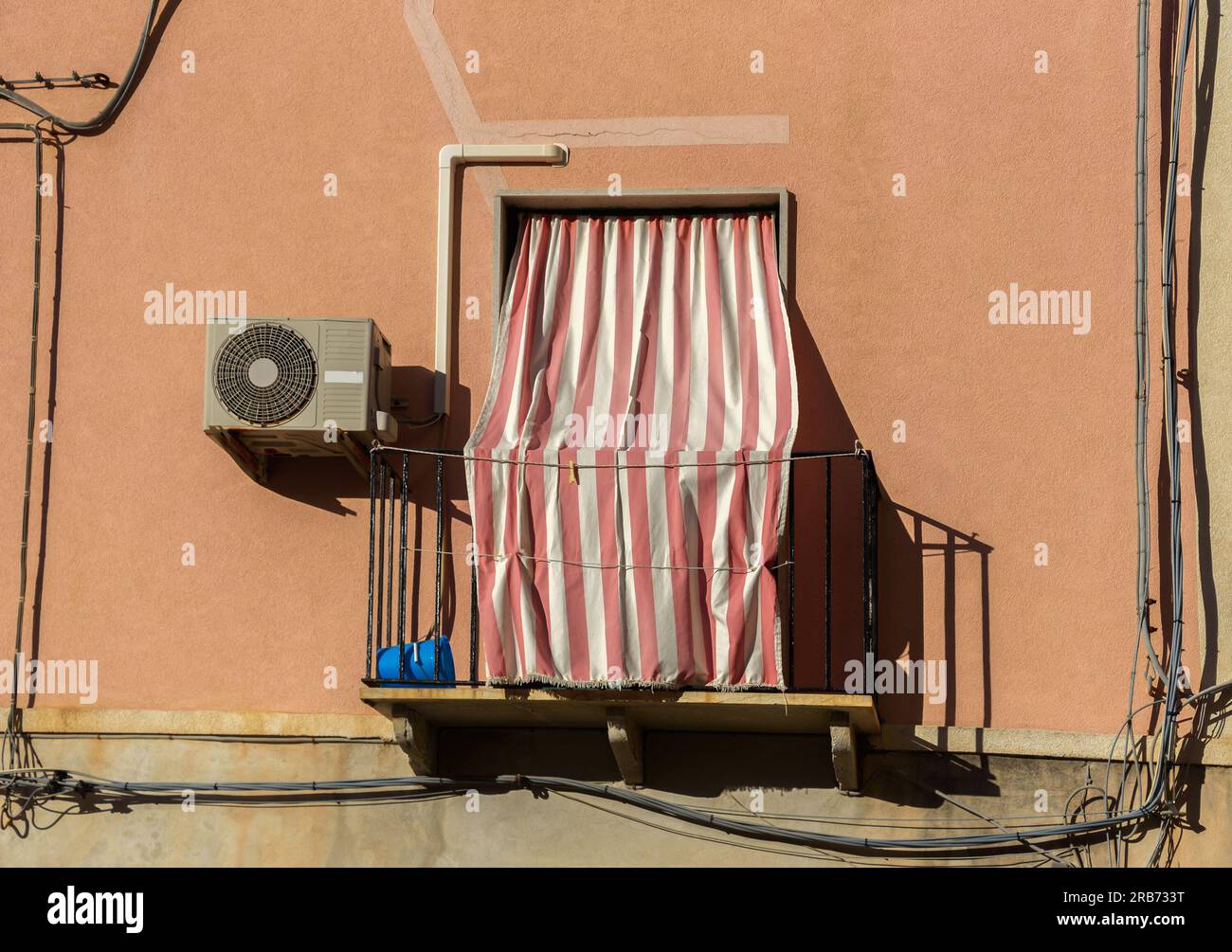 Des rideaux classiques ferment la fenêtre du balcon par une chaude journée en Italie. Banque D'Images