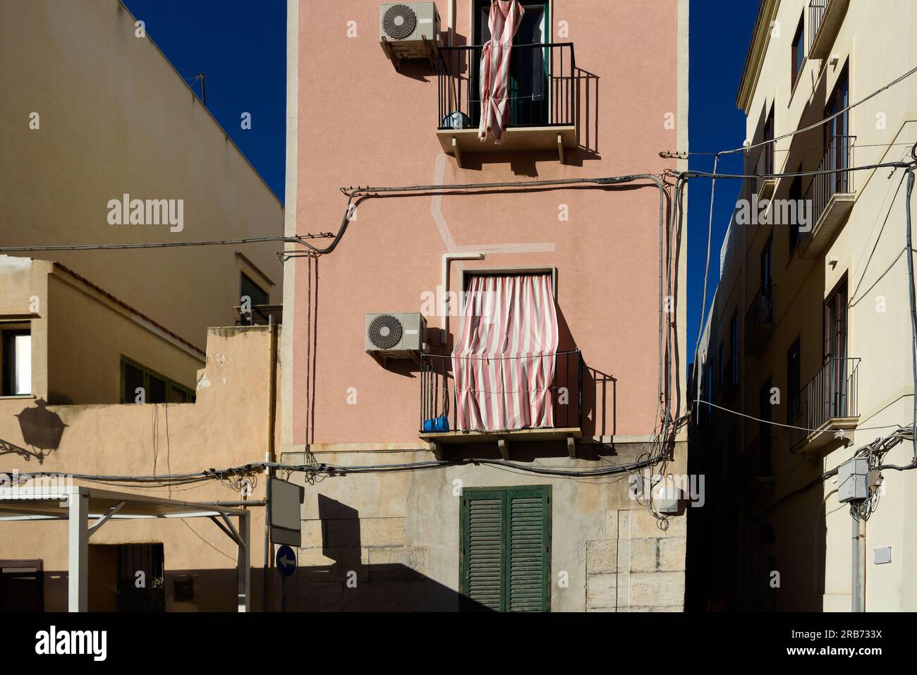 Des rideaux classiques ferment la fenêtre du balcon par une chaude journée en Italie. Banque D'Images