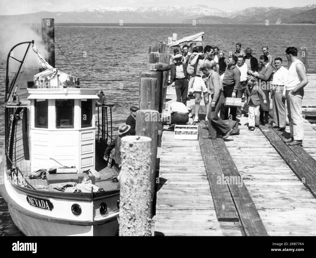 Lake Tahoe, Californie : 29 mars 1934 le concurrent poids lourd Max Baer (avec sac de courrier à l'épaule) et ses amis sur le quai à Globins Hotel sur le lac Tahoe où il s'entraîne pour son prochain combat avec le champion Primo Carnera. Le courrier est livré deux fois par semaine. Banque D'Images