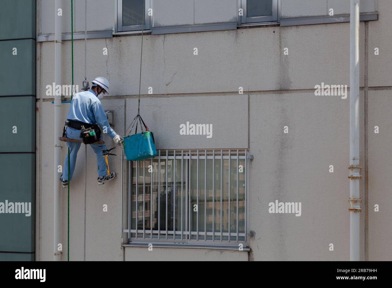 Un technicien d'accès par corde qui répare l'extérieur d'un bâtiment à Ebisu, Tokyo, Japon. Banque D'Images